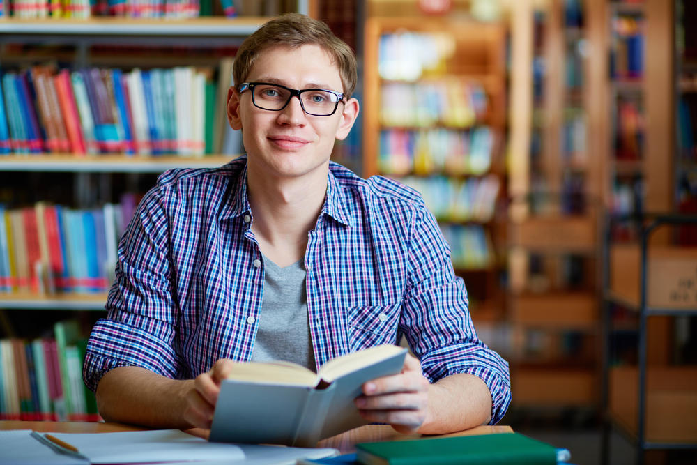 戴眼镜的男学生在图书馆里看书摄影图